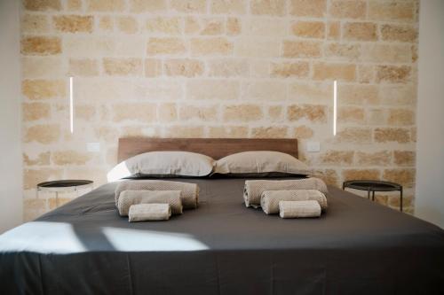 a bed with two pillows on it with a brick wall at Petrina Home - Suite Rooms Barletta in Barletta