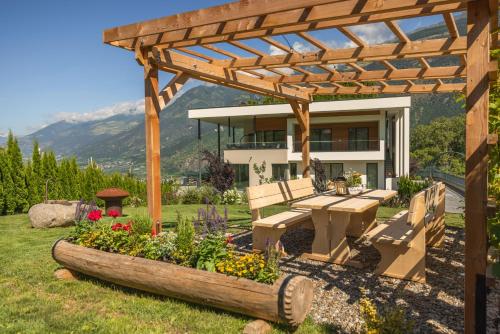 a garden with a wooden pergola and a table and bench at Ortsried-Hof in Laces