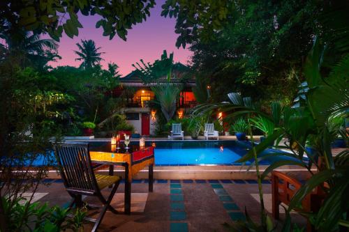 a table and a chair next to a swimming pool at The Cockatoo Nature Resort & Spa in Siem Reap