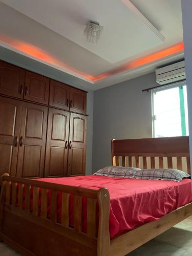 - une chambre avec un lit en bois et une couverture rouge dans l'établissement Casa na praia no Guarujá, à Guarujá