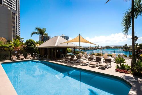 a swimming pool with chairs and umbrellas on a building at Moorings On Cavill Surfers Paradise in Gold Coast