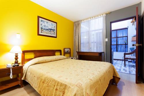 1 dormitorio con cama y pared amarilla en Hotel Francés La Maison, en Pasto