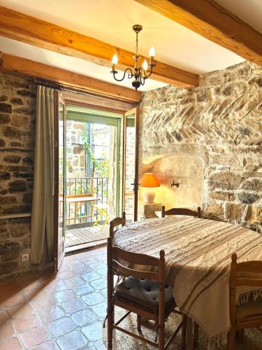 - une chambre dotée d'un mur en pierre avec un lit et des chaises dans l'établissement Loustalet, à Saint-Jean-de-la-Blaquière