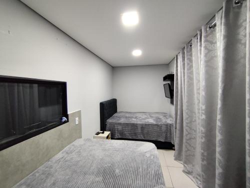 ein Schlafzimmer mit einem Bett und einem Flachbildfernseher in der Unterkunft Casa de praia - Bombinhas in Bombinhas