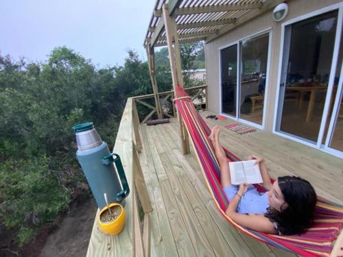 a woman laying in a hammock with a book at Nio de Baixo in La Pedrera