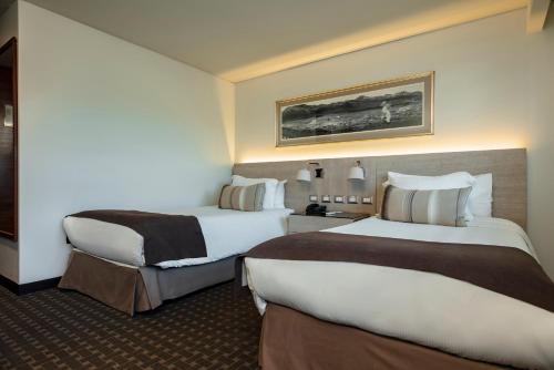 a hotel room with two beds in a room at Hotel Los Españoles Plus in Santiago
