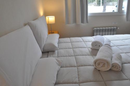 a white bed with towels on it with a window at Aparts Merkaba in El Chalten