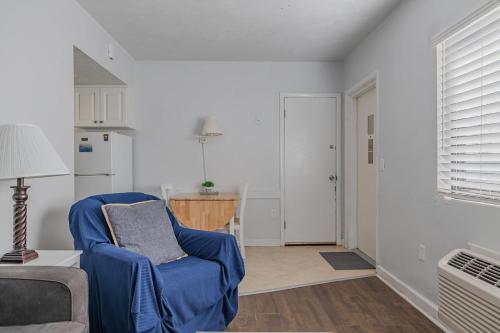 a living room with a blue chair and a kitchen at Coastal Waters in New Smyrna Beach