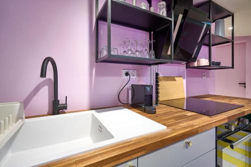 - une cuisine avec un évier blanc et des murs violets dans l'établissement Appart InstaGood by La Villa Orange, à Carcassonne