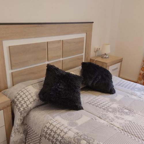 - un lit avec 2 oreillers noirs dans l'établissement Apartamento ESPERANZA DE LA YEDRA, à Jerez de la Frontera