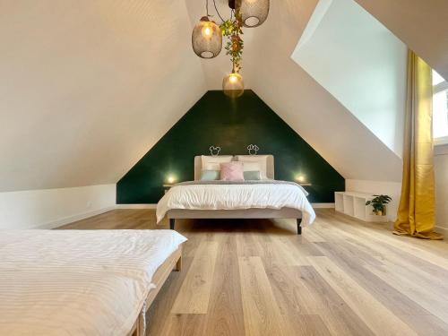 a attic bedroom with two beds and a green wall at Cozy home Disney in Chalifert