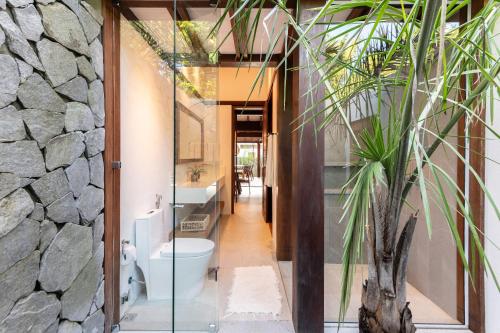 a bathroom with a toilet and a stone wall at Colibri Beach Villas in Ilha de Boipeba