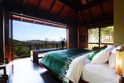 a bedroom with a bed and a large window at Villa Zolitude Resort & Spa - SHA Extra Plus in Chalong