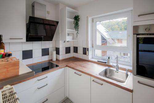 a kitchen with white cabinets and a sink and a window at Stylishes Village Apartment in Wiesloch
