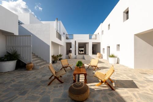 a courtyard of a house with chairs and a table at Cavo Piso Livadi in Piso Livadi