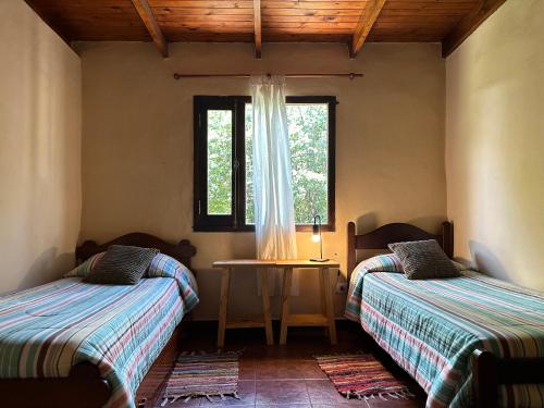 a room with two beds and a window at Los ciruelos - Casas de Motaña in Tafí del Valle