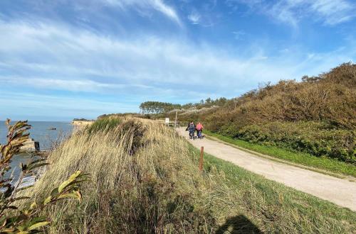 two people walking down a path next to the water at Sonnenblume in der Seefahrtschule in Wustrow