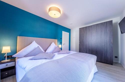 a bedroom with a large white bed with a blue wall at Ferienwohnung Meersinn in Wustrow-Komfort, Meerblick und Wellness in Strandnähe in Wustrow