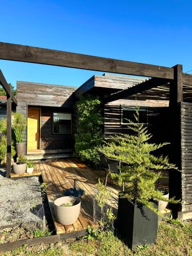 a house with a wooden deck with a pine tree at Cabaña Luna de Lobos in Pichilemu