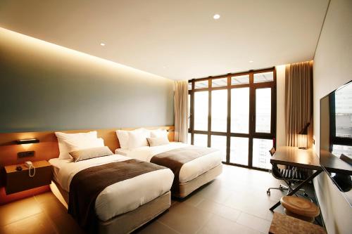 a hotel room with two beds and a television at MD HOTEL Dongtan in Hwaseong