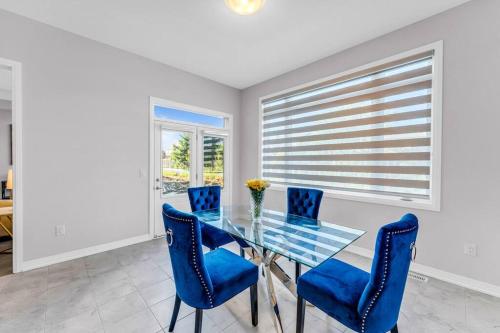 a dining room with a glass table and blue chairs at Executive Brand New House 5 Bedrooms and Office in Cambridge
