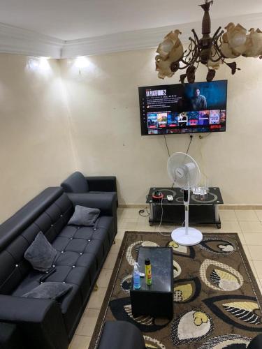 un soggiorno con un divano nero e una TV di studio meublé a Dakar