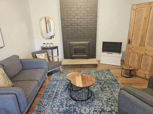 a living room with a couch and a table and a fireplace at RoseIris Cottage - City Charm in Central West Hobart in West Hobart