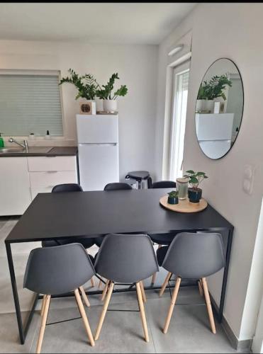 - une table et des chaises noires dans une cuisine avec un miroir dans l'établissement MAISON NEUVE 15 min STRASBOURG, à Geudertheim