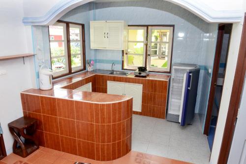 a kitchen with wooden cabinets and a sink and a refrigerator at New Sunrise Village in Mae Nam