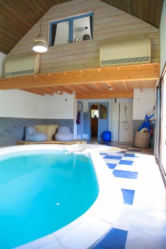 a swimming pool in a house with a wooden ceiling at Gîte de Guernevez in Hôpital-Camfrout