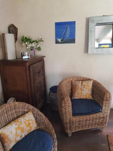 a living room with two wicker chairs and a cabinet at Gîte de Guernevez in Hôpital-Camfrout