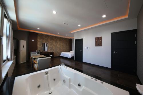 a large bath tub in a room with a bedroom at Hotel memory Jumunjin- Welcome drink provided in Gangneung