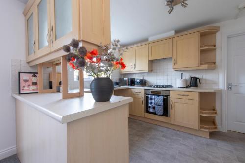 a kitchen with a vase with flowers on a counter at Stunning 5 bedroom detached house in Hornchurch in Romford
