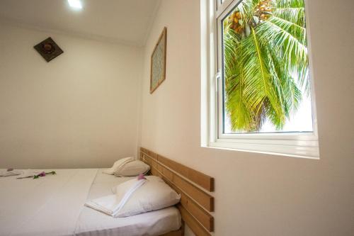 a bedroom with a bed and a window with a palm tree at Faza View Inn, Maafushi in Maafushi