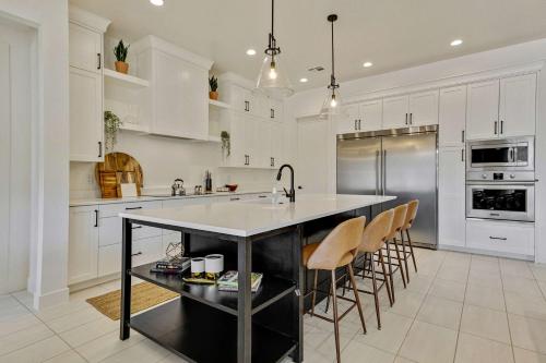 a kitchen with white cabinets and a island with bar chairs at Private HotTub By Copper Rock Golf Course in Hurricane