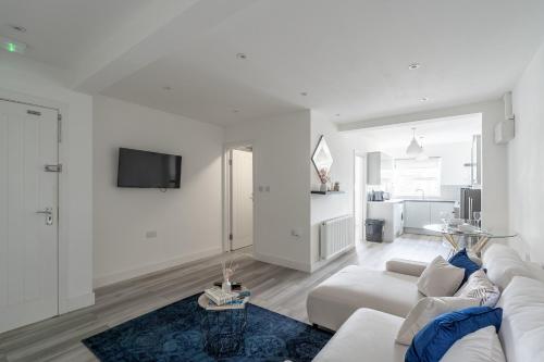 a white living room with a white couch and a blue rug at Cozy Downtown Apartment in Rochester