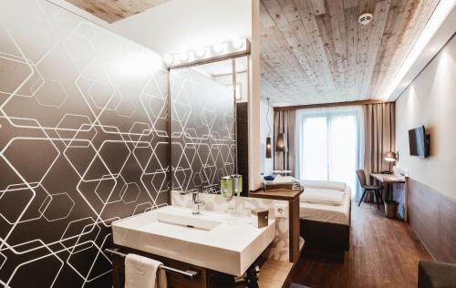 uma casa de banho com um lavatório e uma cama num quarto em arte Hotel Kufstein em Kufstein
