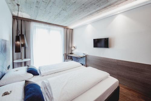 a hotel room with two beds and a television at arte Hotel Kufstein in Kufstein