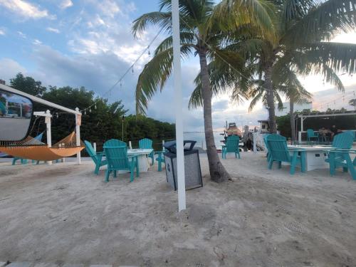 a group of chairs and tables and a hammock on the beach at Gallego Deluxe Rental in Key Largo