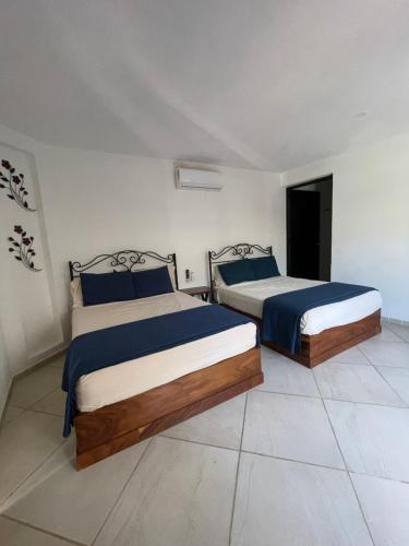 two beds in a white room with blue sheets at Casa Kahakai 2 in Chacala