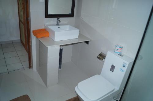 a white bathroom with a sink and a toilet at Gästehaus Isabella in Beruwala