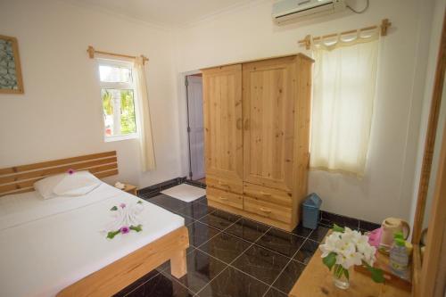 a bedroom with a bed and a wooden cabinet at Faza View Inn, Maafushi in Maafushi