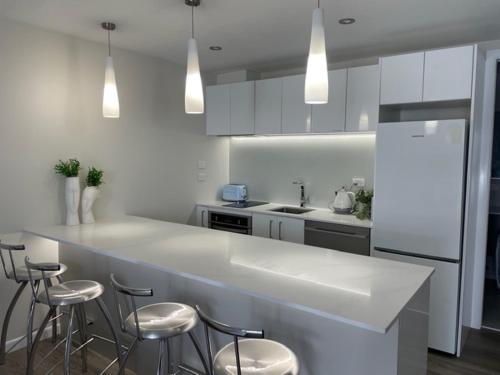 a kitchen with a white counter and stools at Two Bedroom Guest House in Remuera Auckland in Auckland