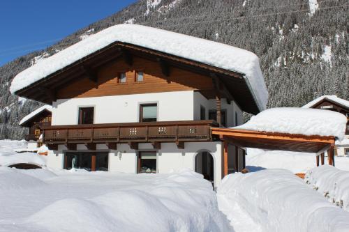 a house covered in snow in front of a mountain at Apartment Berger in Sankt Veit in Defereggen