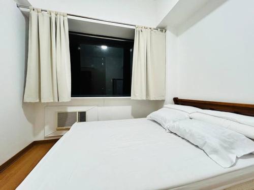 a white bed in a room with a window at Budget Accommodation at Ace Suites by the Famous Indoor Water Spa in Manila