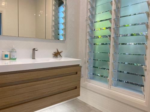 a bathroom with a sink and a glass shower curtain at Sea Palms Beach House with pool in Port Macquarie