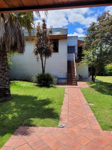 a house with a palm tree and a brick walkway at Casa con piscina en Piriápolis in Piriápolis