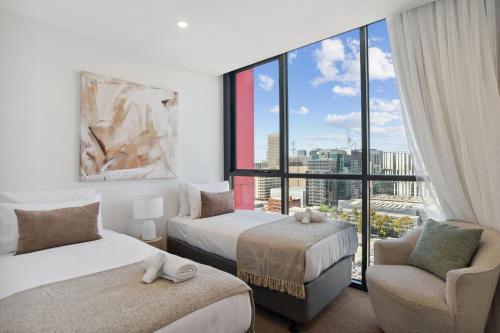Un dormitorio con dos camas y una silla y una ventana. en Blue Pool Escape Stunning Views, en Adelaida