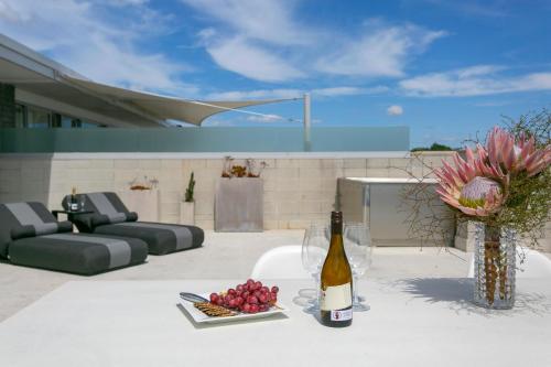 a bottle of wine and a plate of fruit on a patio at Sacred Waters Taupo in Taupo