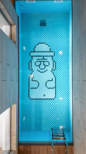a blue tile wall in a bathroom with a picture of a sultan at Eudaimonia Poolvilla Jeju 에다모니아 함덕풀빌라 in Jeju